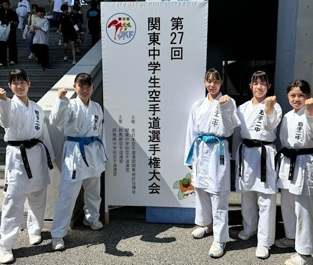 関東大会に来ました。第27回関東中学生空手道選手権大会の看板の前で女子5名が整列しています。