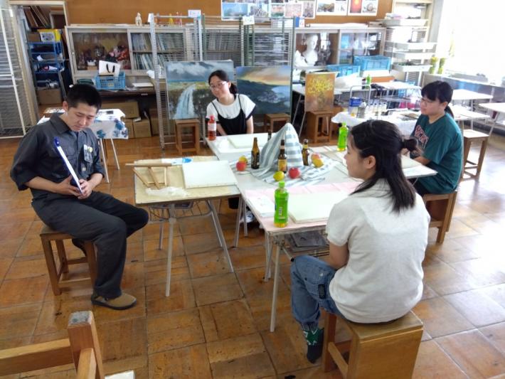 講師の先生が中学生3人に油絵の説明をしています。