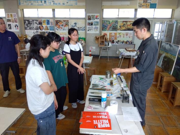 講師の先生が中学生3人に油絵で使う道具の説明をしています。