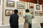 福祉会館の作品展示用パネル。展示された作品に見入っている人がいる画像。